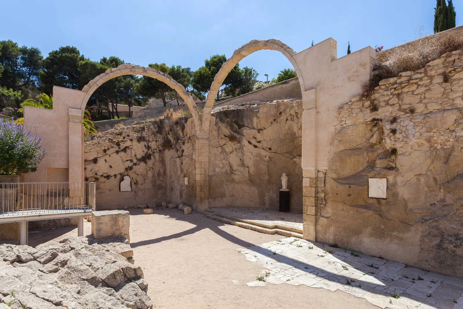 Due archi in pietra tra le rovine all'interno del Castello di Santa Bárbara, Alicante; una fotografia generale del castello sopra il quartiere